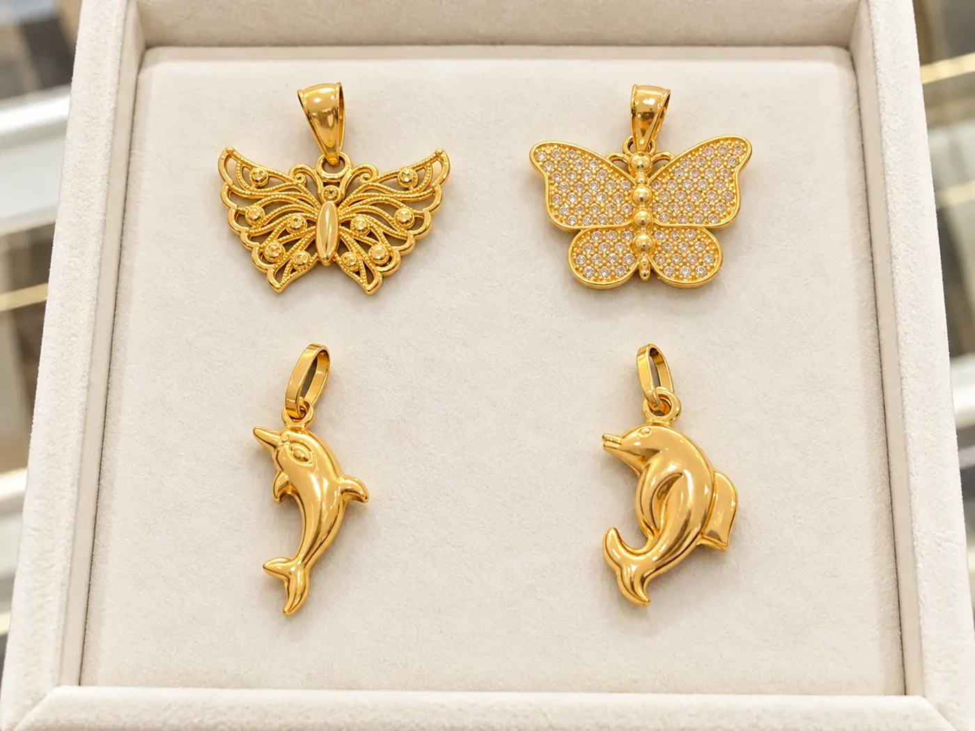 Gold filigree and diamond butterfly pendants with two gold dolphin pendants in an ivory box