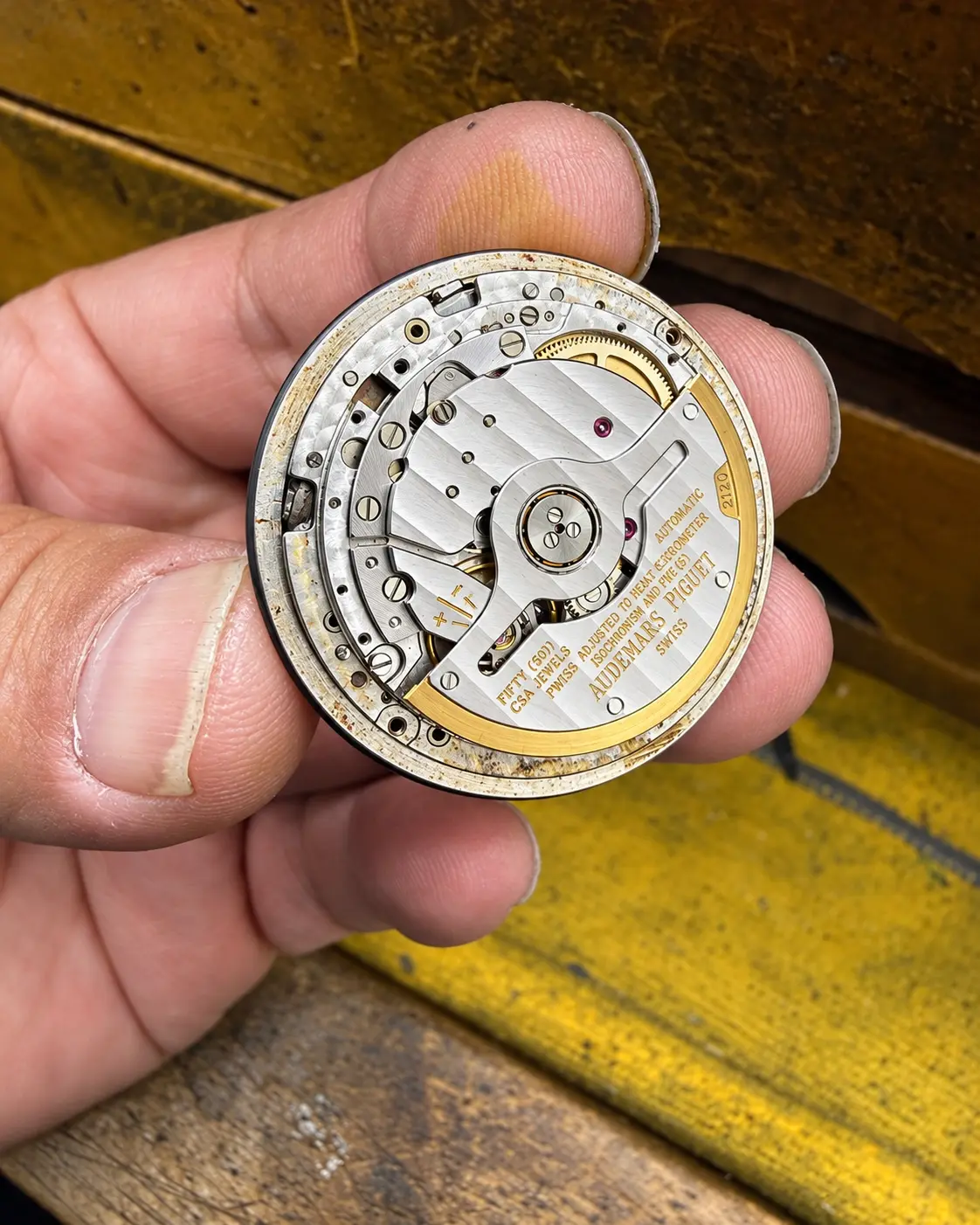 Fine automatic movement held in hand over the bench
