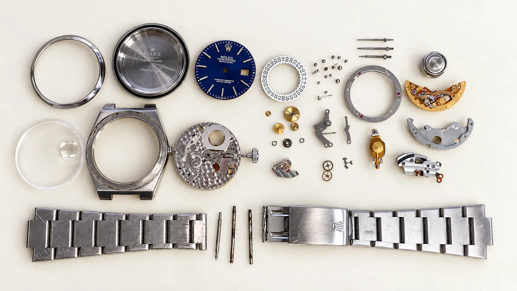 Watch fully disassembled — case, blue dial, movement and bracelet laid out